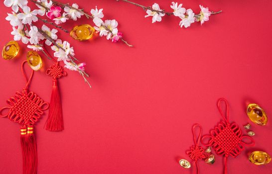 Design concept of Chinese lunar new year - Beautiful Chinese knot with plum blossom isolated on red background, flat lay, top view, overhead layout.