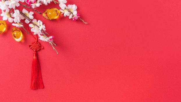 Design concept of Chinese lunar new year - Beautiful Chinese knot with plum blossom isolated on red background, flat lay, top view, overhead layout.