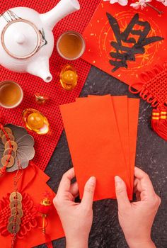 Design concept of Chinese lunar January new year - Woman holding, giving red envelopes (ang pow, hong bao) for lucky money, top view, flat lay, overhead above. The word 'chun' means coming spring.