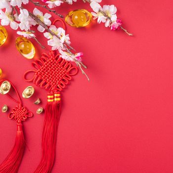 Design concept of Chinese lunar new year - Beautiful Chinese knot with plum blossom isolated on red background, flat lay, top view, overhead layout.