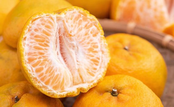 Fresh, beautiful orange color tangerine on bamboo sieve over dark wooden table. Seasonal, traditional fruit of Chinese lunar new year, close up.