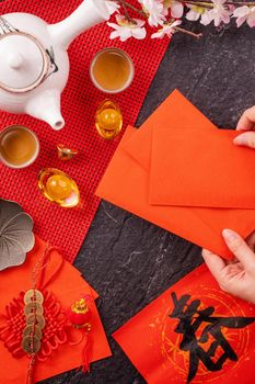 Design concept of Chinese lunar January new year - Woman holding, giving red envelopes (ang pow, hong bao) for lucky money, top view, flat lay, overhead above. The word 'chun' means coming spring.