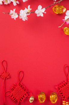 Design concept of Chinese lunar new year - Beautiful Chinese knot with plum blossom isolated on red background, flat lay, top view, overhead layout.