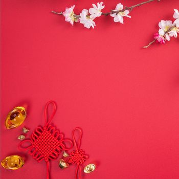 Design concept of Chinese lunar new year - Beautiful Chinese knot with plum blossom isolated on red background, flat lay, top view, overhead layout.