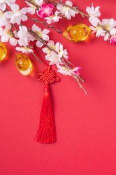 Design concept of Chinese lunar new year - Beautiful Chinese knot with plum blossom isolated on red background, flat lay, top view, overhead layout.