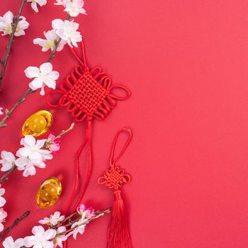 Design concept of Chinese lunar new year - Beautiful Chinese knot with plum blossom isolated on red background, flat lay, top view, overhead layout.