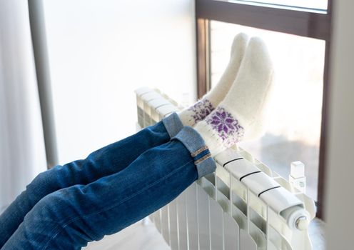 Woman warming up with feet on heater