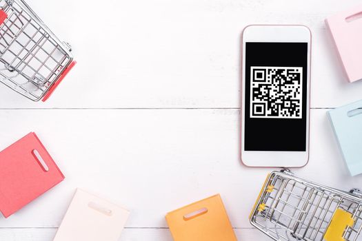 Abstract online shopping, mobile payment with QR code design concept element, colorful cart, paper bag on wooden table background, top view, flat lay