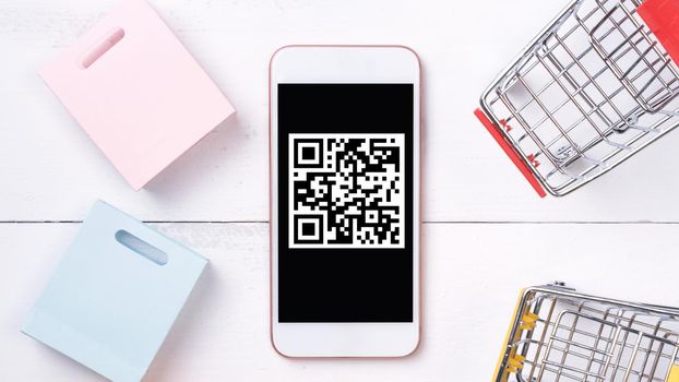 Abstract online shopping, mobile payment with QR code design concept element, colorful cart, paper bag on wooden table background, top view, flat lay