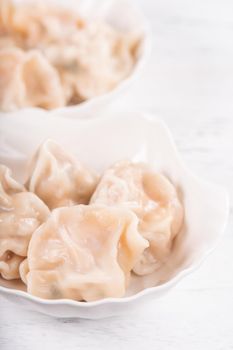 Fresh, delicious boiled pork, shrimp gyoza dumplings on white background with soy sauce and chopsticks, close up, lifestyle. Homemade design concept.