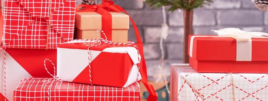 Decorated Christmas tree with wrapped beautiful red and white gifts at home with black brick wall, festive design concept, close up.