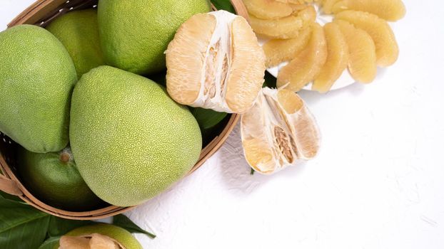 Fresh pomelo, pummelo, grapefruit, shaddock on white cement background in bamboo basket. Autumn seasonal fruit, top view, flat lay, tabletop shot.