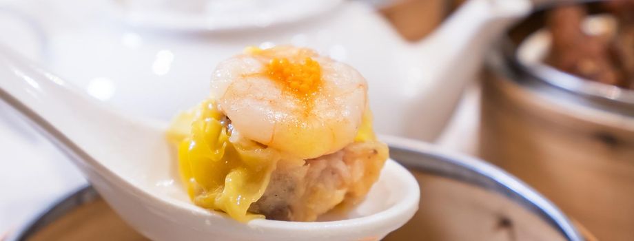 Siu Mai, one of Dim Sum yum cha, pork and shrimp steamed dumplings on restaurant house white background table for breakfast, lifestyle, close up.