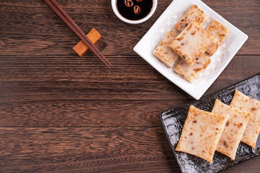 Delicious turnip cake, Chinese traditional radish cake in restaurant with soy sauce for new year's dishes, close up, copy space, top view, flat lay.
