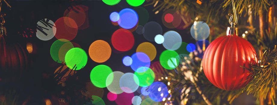 Beautiful Christmas decor concept, bauble hanging on the Christmas tree with sparkling light spot, blurry dark black background, macro detail, close up.