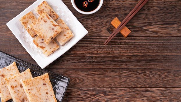 Delicious turnip cake, Chinese traditional radish cake in restaurant with soy sauce for new year's dishes, close up, copy space, top view, flat lay.