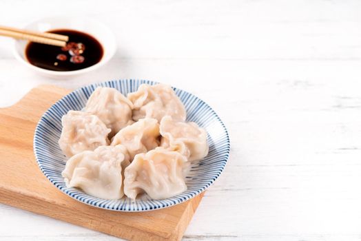 Fresh, delicious boiled pork, shrimp gyoza dumplings on white background with soy sauce and chopsticks, close up, lifestyle. Homemade design concept.