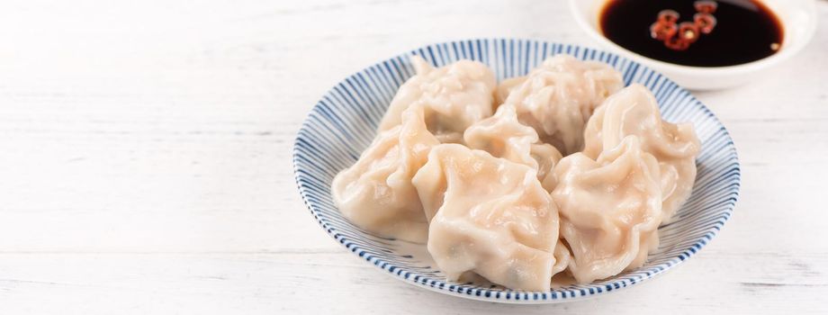 Fresh, delicious boiled pork, shrimp gyoza dumplings on white background with soy sauce and chopsticks, close up, lifestyle. Homemade design concept.