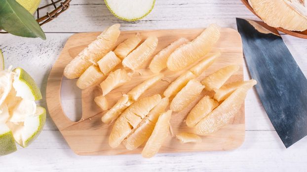 Fresh peeled pomelo, pummelo, grapefruit, shaddock on bright wooden background. Autumn seasonal fruit, top view, flat lay, tabletop shot.
