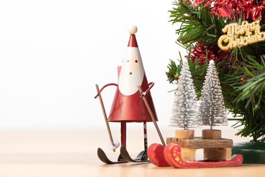 Decorated cute Christmas tree on a wooden floor with white background and toys, blank for festive design concept, close up.