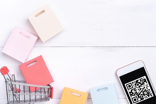 Abstract online shopping, mobile payment with QR code design concept element, colorful cart, paper bag on wooden table background, top view, flat lay