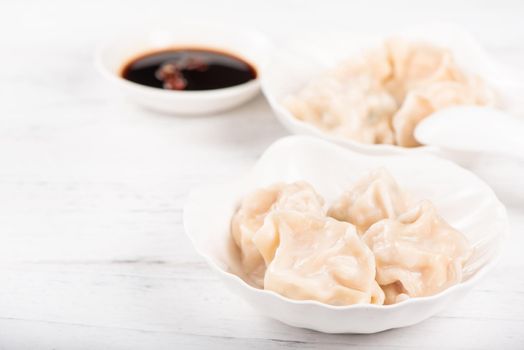 Fresh, delicious boiled pork, shrimp gyoza dumplings on white background with soy sauce and chopsticks, close up, lifestyle. Homemade design concept.