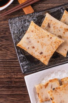 Delicious turnip cake, Chinese traditional radish cake in restaurant with soy sauce for new year's dishes, close up, copy space, top view, flat lay.