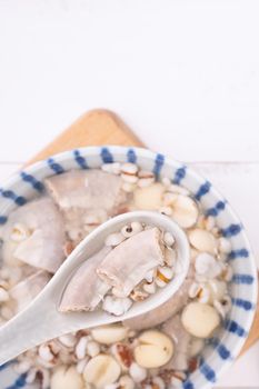 Tasty Four Tonics Herb Flavor Soup, Taiwanese traditional food with herbs, pork intestines on white wooden table, close up, flat lay, top view.