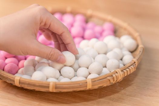 An Asia woman is making Tang yuan, yuan xiao, Chinese traditional food rice dumplings in red and white for lunar new year, winter festival, close up.