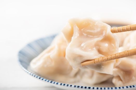Fresh, delicious boiled pork, shrimp gyoza dumplings on white background with soy sauce and chopsticks, close up, lifestyle. Homemade design concept.