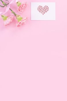 Beautiful, fresh elegant carnation flower bouquet with white greeting thanks gift card isolated on bright pink color background, top view, flat lay concept.