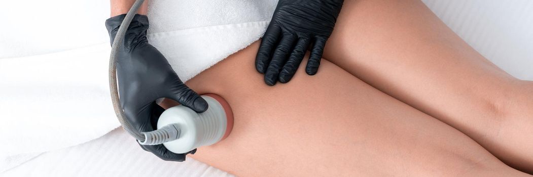 Beautiful woman having cavitation, procedure removing cellulite on legs and buttocks at beauty clinic