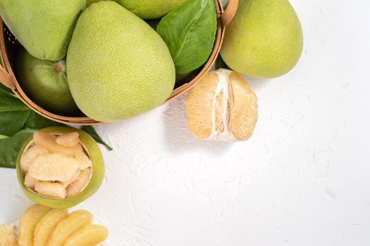 Fresh peeled pomelo, pummelo, grapefruit, shaddock on bright wooden background. Autumn seasonal fruit, top view, flat lay, tabletop shot.