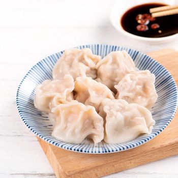 Fresh, delicious boiled pork gyoza dumplings, jiaozi on white background with soy sauce and chopsticks, close up, lifestyle. Homemade design concept.
