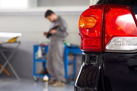 Car in auto repair shop with blurred mechanic on a background
