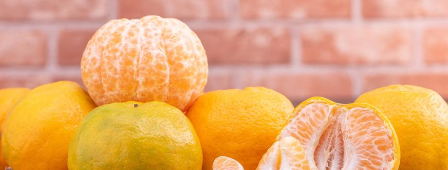 Peeled tangerines in a bamboo sieve basket on dark wooden table with red brick wall background, Chinese lunar new year fruit design concept, close up.