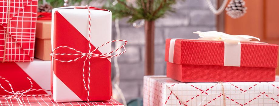 Decorated Christmas tree with wrapped beautiful red and white gifts at home with black brick wall, festive design concept, close up.