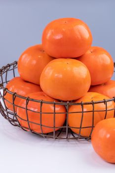 Fresh beautiful sliced sweet persimmon kaki isolated on white kitchen table with gray blue background, Chinese lunar new year design concept, close up.