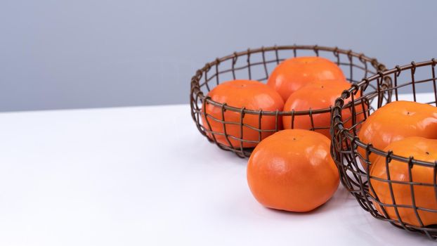 Fresh beautiful sliced sweet persimmon kaki isolated on white kitchen table with gray blue background, Chinese lunar new year design concept, close up.