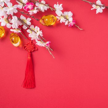 Design concept of Chinese lunar new year - Beautiful Chinese knot with plum blossom isolated on red background, flat lay, top view, overhead layout.