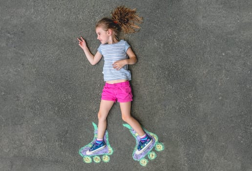 Sweet girl in roller skates painted with chalk on asphalt. top view