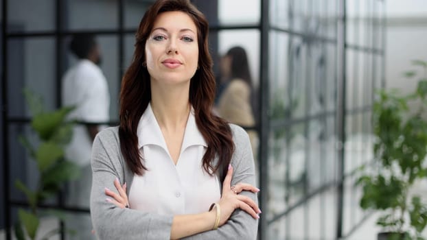 Portrait of a serious lady posing against the backdrop of a modern office.