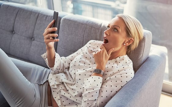 You cant believe everything you read online. a mature woman using her cellphone while relaxing at home