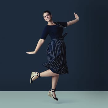Skipping along towards success. Studio portrait of a corporate businesswoman posing against a dark background