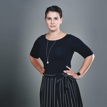Firm in who she is and what she believes in. Studio portrait of a confident young businesswoman posing against a grey background