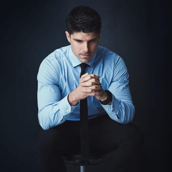Some decisions require deep thought. Studio shot of a young businessman looking thoughtful against a dark background