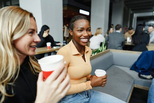 Two young women friends enjoying coffee together in a coffee shop close up