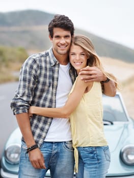 Carefree youth. A romantic young couple standing alongside their convertible while on a roadtrip