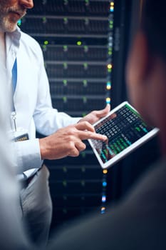 Find the solution, save the day. Closeup shot of an unrecognisable man using a digital tablet while working with a colleague in a server room