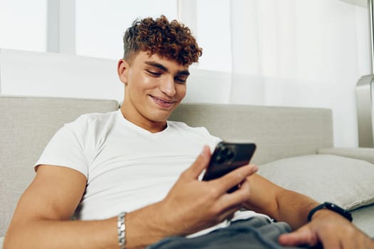 man selfies student sofa curly freelancer holding text message sports couch smartphone cell home laptop technology adult